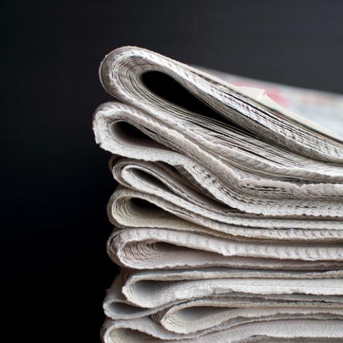 Stack of Newspapers in front of a black background with copy space
